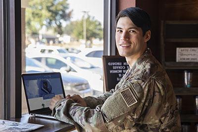 A UWF student and military veteran visits the UWF site from a laptop.